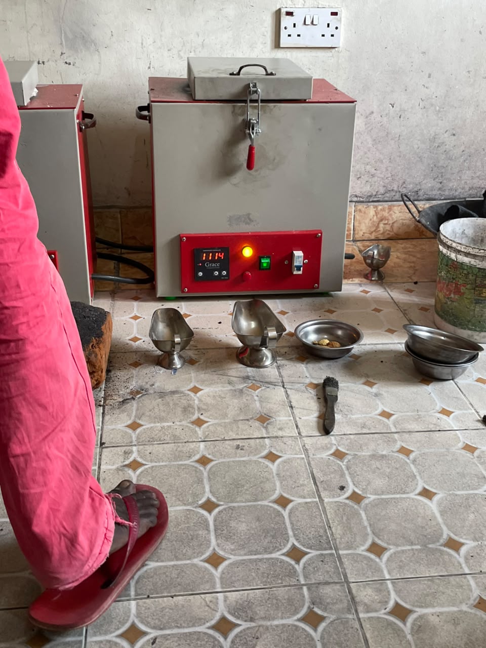 Electric smelting furnace reading 1114 degrees with crucibles and pans on the smelt house floor